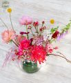 Luftiger Tafelaufsatz mit Saisonblumen in Glaskugel (rosa, rot, pfirsich)