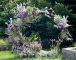 Modern hatszögletű boldogságkapu lila virágokkal (Budapest, agapantusz, delphinium, allium, anthurium, rezgő, szegfű)