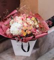 Romantischer, luftiger Blumenstrauß in einer Tasche mit Hortensie, Rose und Lisianthus