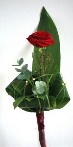 eine einzelne rote Rose mit spezieller Dekoration und eine dünne Glas-Vase