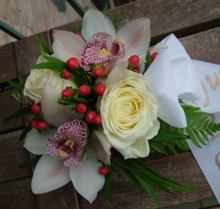 white roses and orchids in a small basket 