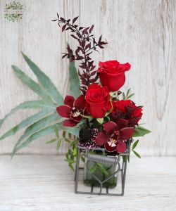 rote Rosen und Cymbidiums in einem Metallherzwürfel