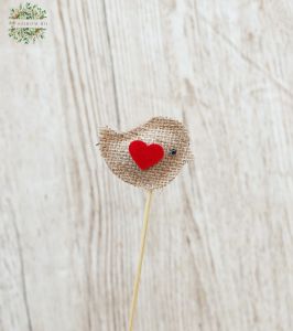a textil bird on a stick with a heart
