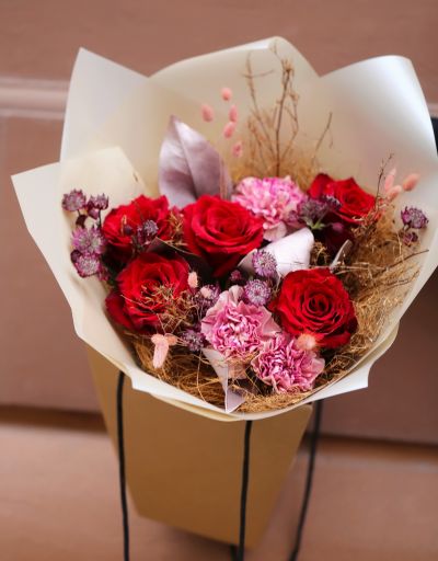 Red rose bouquet in bag with water, in theme of the color of the year Mocha Mousse
