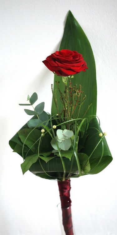 a single red rose with special decoration, and a thin glass vase