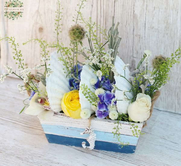 Summer flowers in wooden bowl between seashells, with seahorse