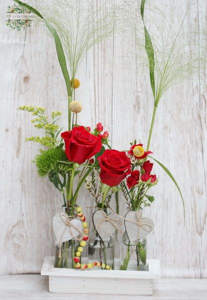 Vasendekorationen mit 3 rote Rosen in einer Holzschale