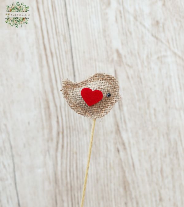a textil bird on a stick with a heart