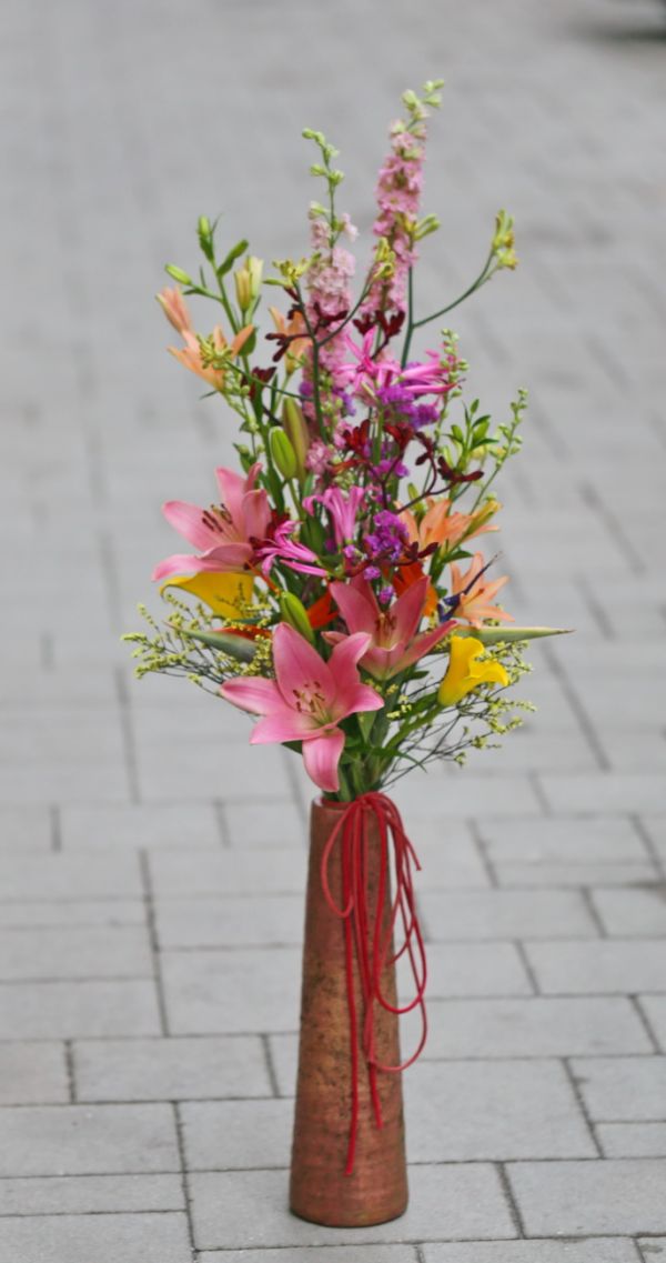 long bright colored bouquet in a long terracotta vase