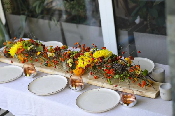 Modern wedding table decoration with vials and autumn flowers (chrysanthems, orange, yellow, burgundy)