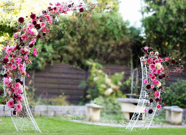 Asymmetrical wedding gate arch with dahlias, zinnias, seasonal berries (pink, burgundy, red)