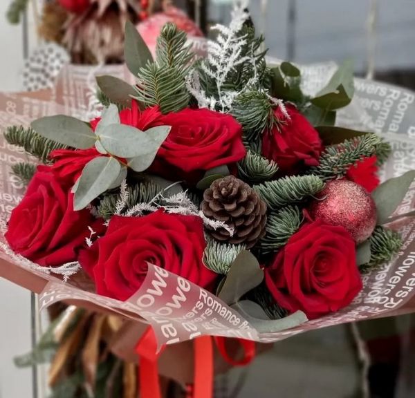 Ein Strauß roter Rosen mit Tannenzapfen und Kugeln
