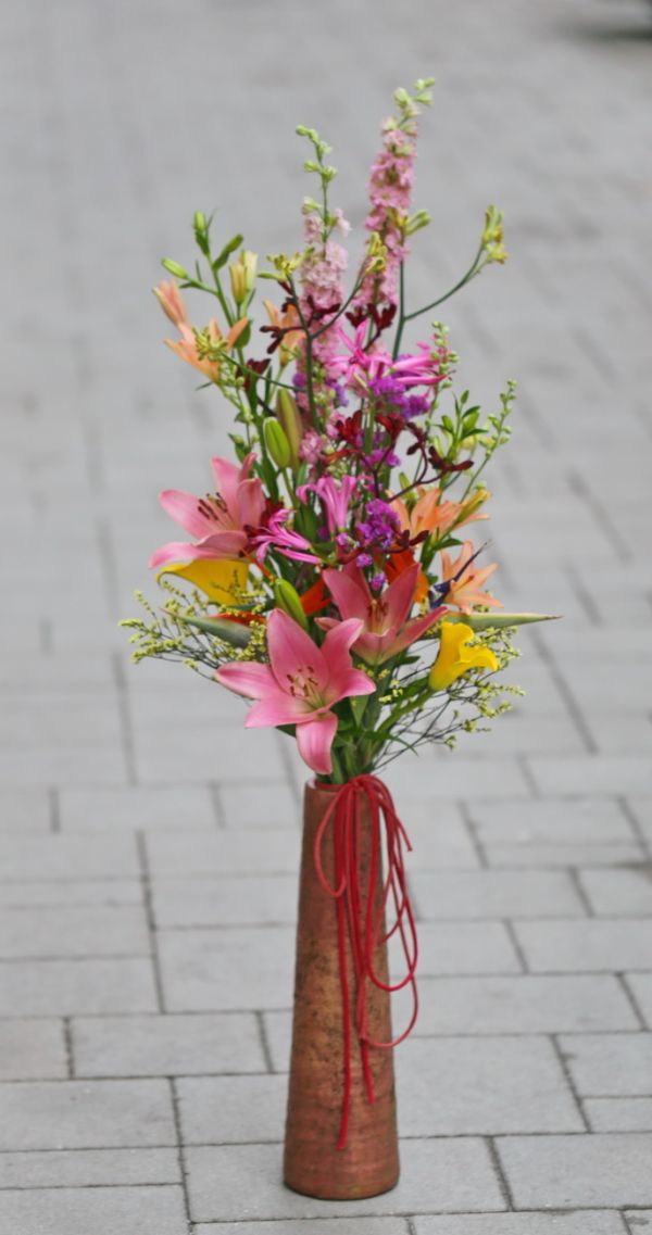 long bright colored bouquet in a long terracotta vase