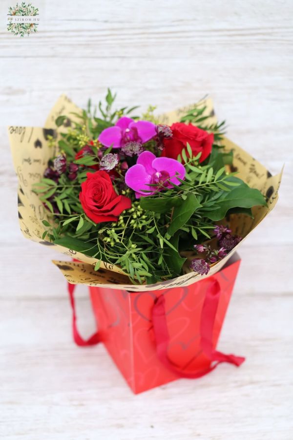 kleiner Orchideen-Rosenstrauß in einer tragbaren Blumentasche mit Henkeln