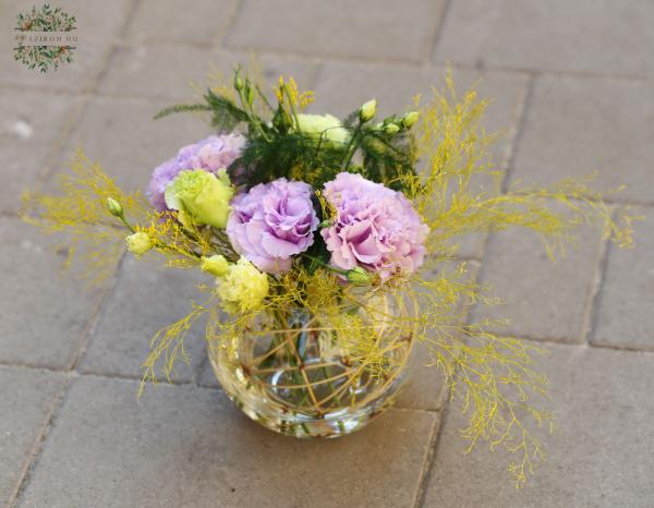 Violette und gelbe Lisianthus Blumen in einer Glaskugel