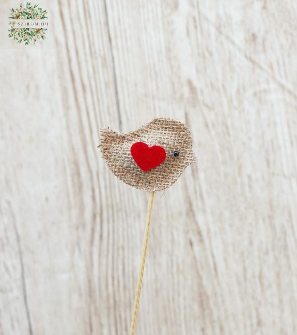 a textil bird on a stick with a heart