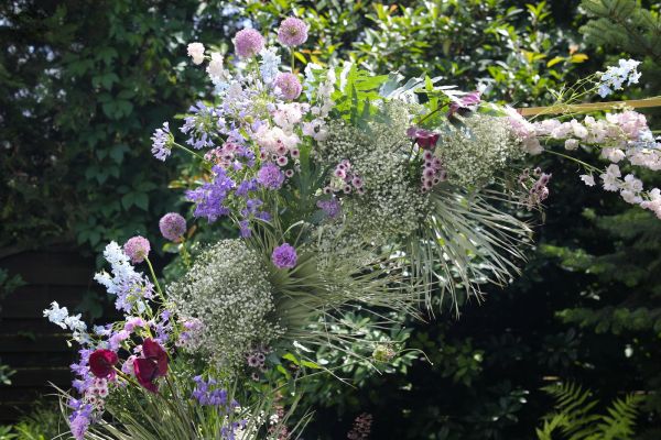Modern hatszögletű boldogságkapu lila virágokkal (Budapest, agapantusz, delphinium, allium, anthurium, rezgő, szegfű)