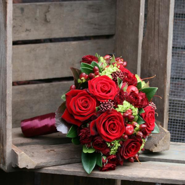Dicht gebundener Strauß roter Rosen mit Äpfeln