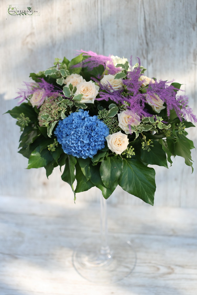 Virágküldés Budapest - Magas esküvői asztaldísz kehely vázában (hortenzia, asparagus, bokros rózsa, barack, lila, kék)