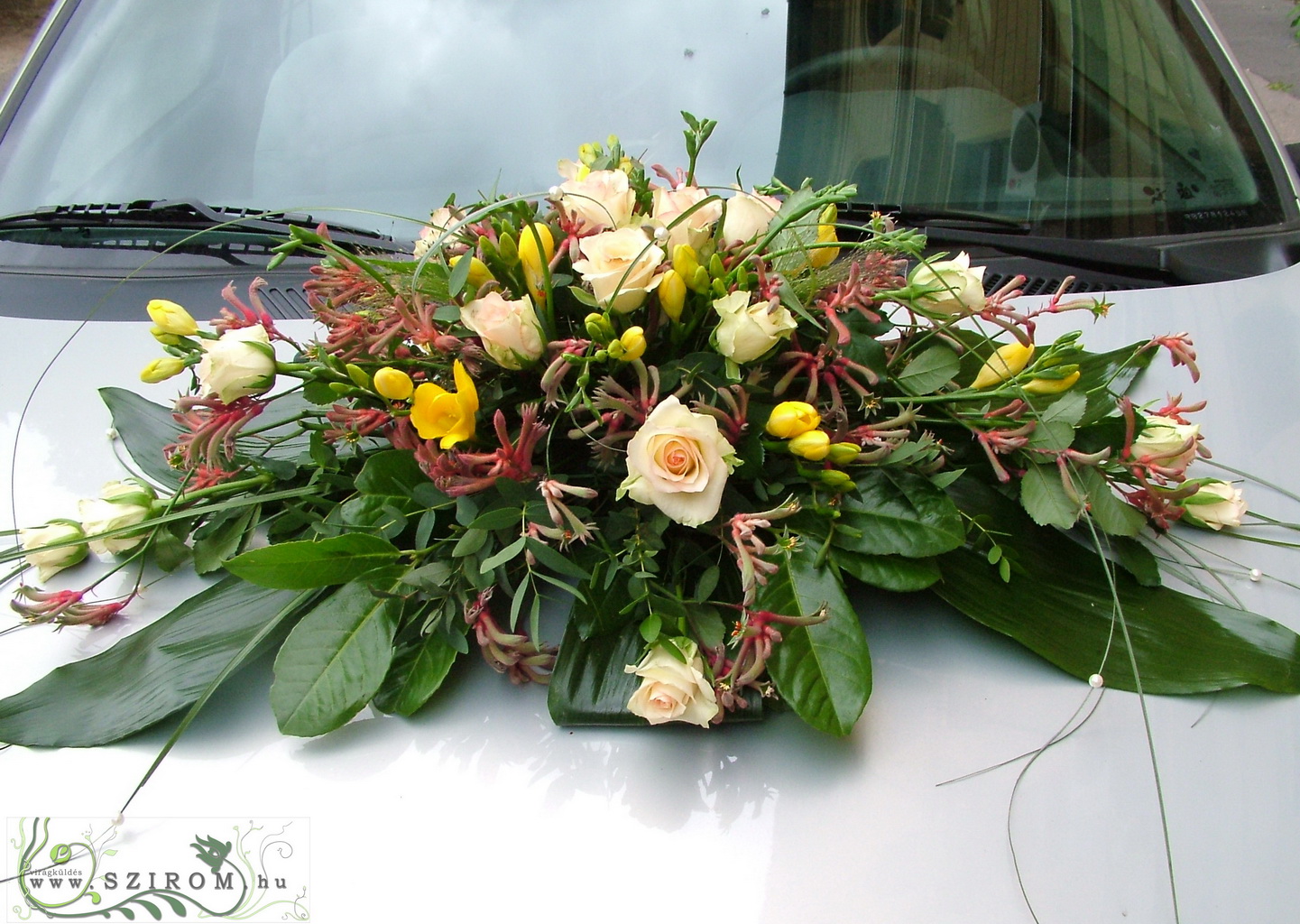 Virágküldés Budapest - ovális autódísz rózsával, kengurumanccsal (frézia, sárga, barack)